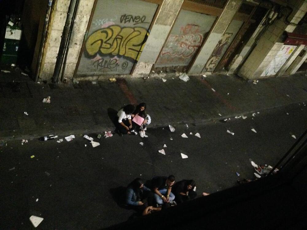 Jóvenes sentados en la acera de Macías Picavea, con la calle llena de suciedad.
