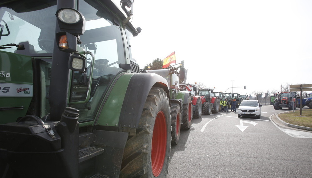 Un taxi circula junto a la tractorada en Valladolid.  / J.T.