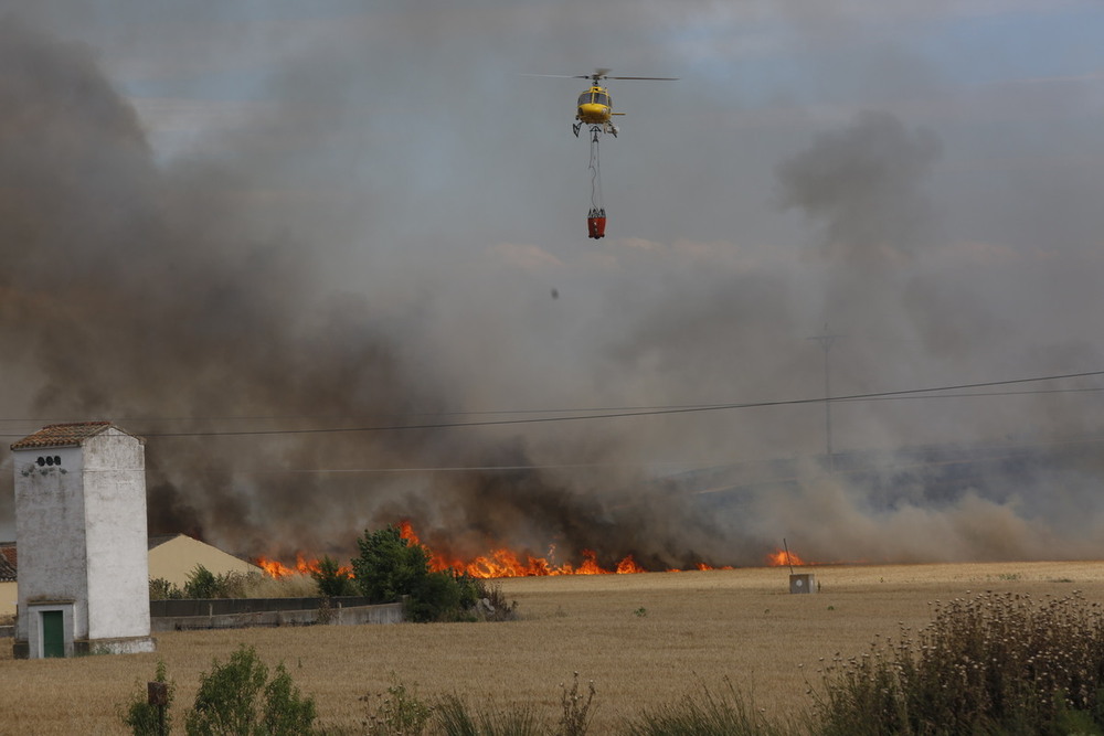 Un helicóptero descarga agua sobre las llamas.